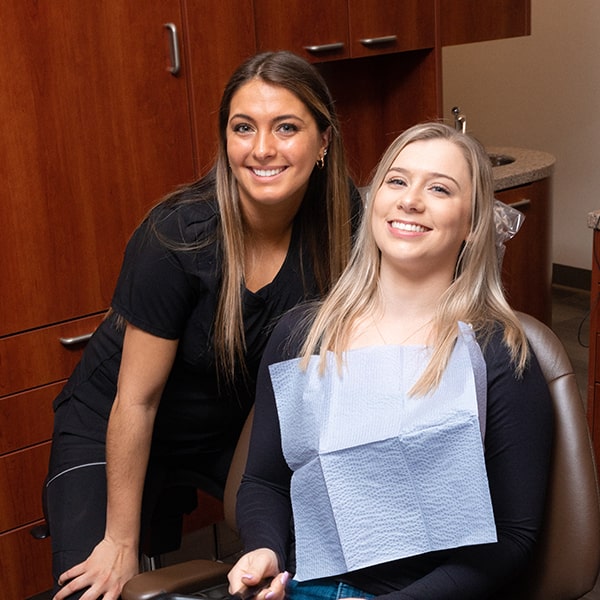 One of our assistants smiling next to a woman in the dental office