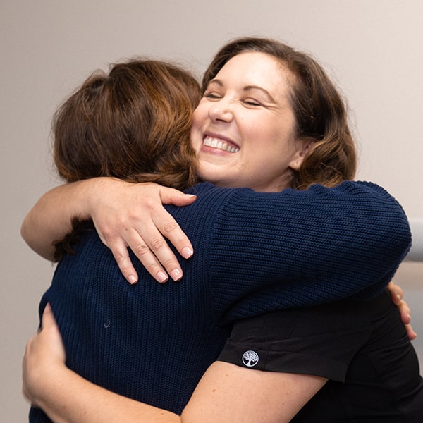 Dr. Kristy Gretzula hugging one of her patients in the dental office