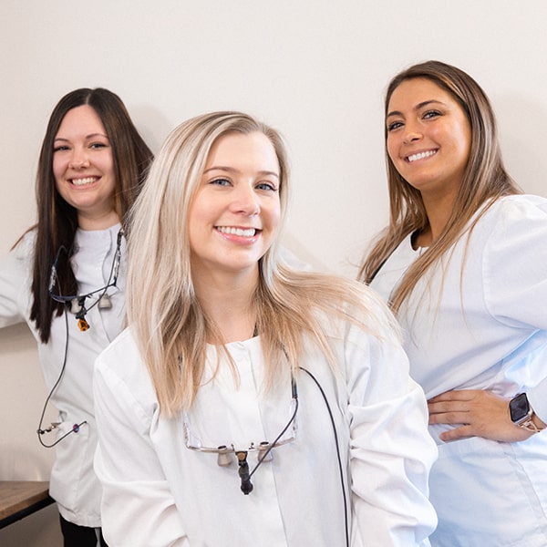 Three of our dental assistants smiling while wearing their uniform