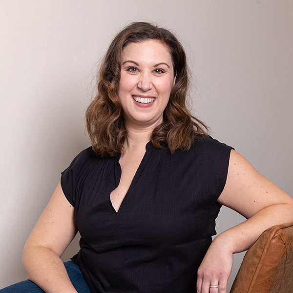 Dr. Kristy Gretzula sitting on a sofa while smiling